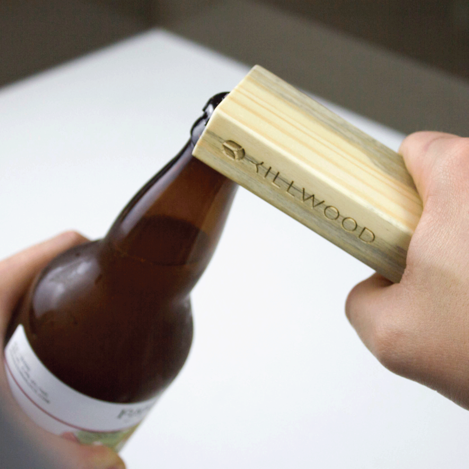 Hand using a wooden bottle opener on a bottle