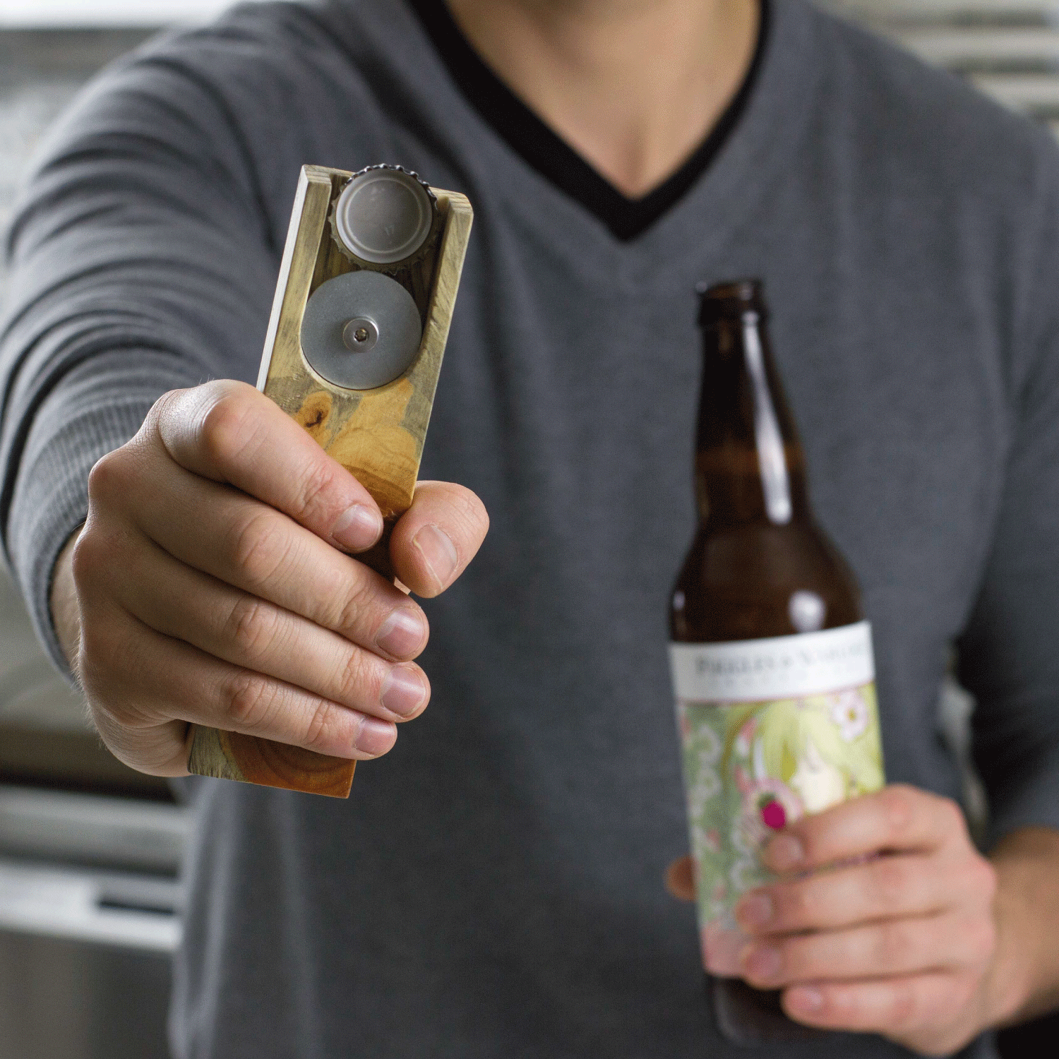 Person holding a wooden bottle opener and a bottle of beer.